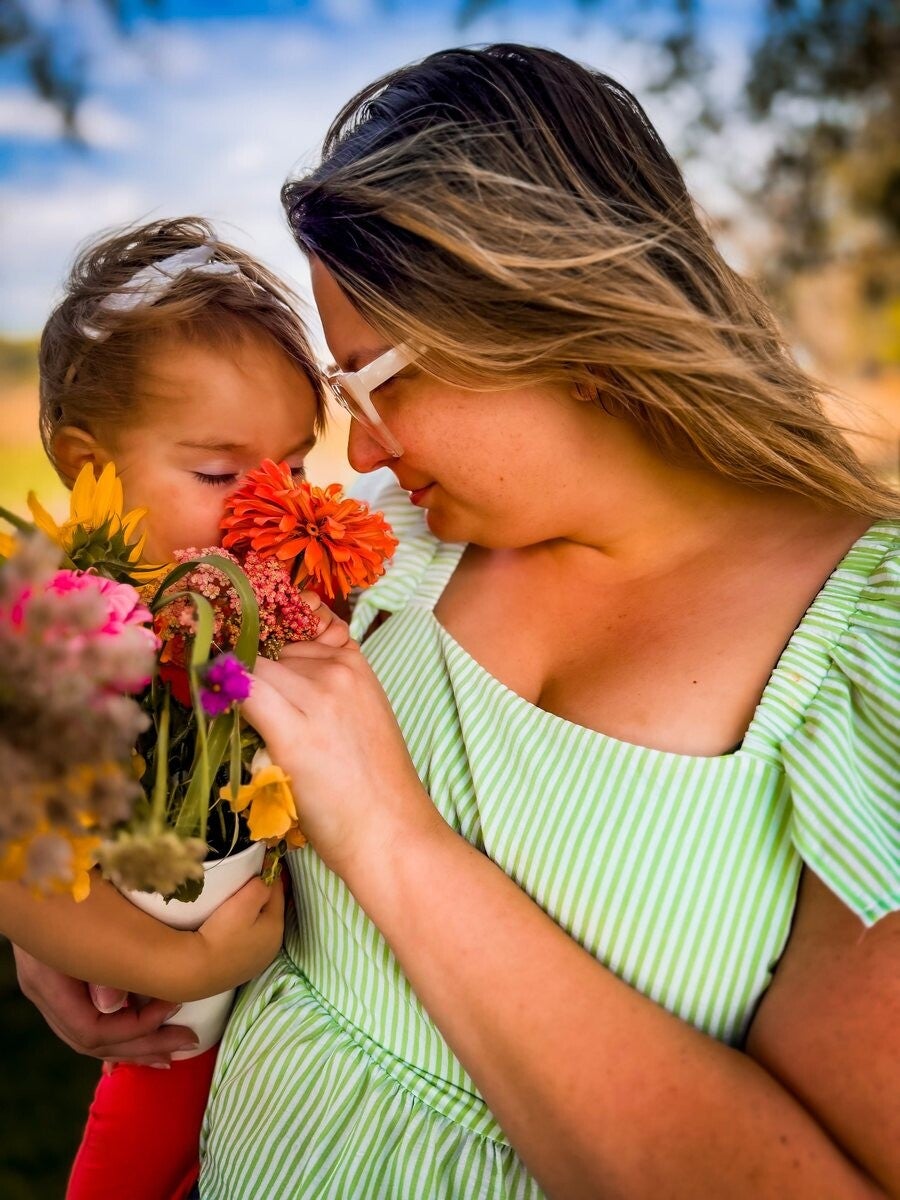 Rachel and her toddler nose-to-nose over a bouquet