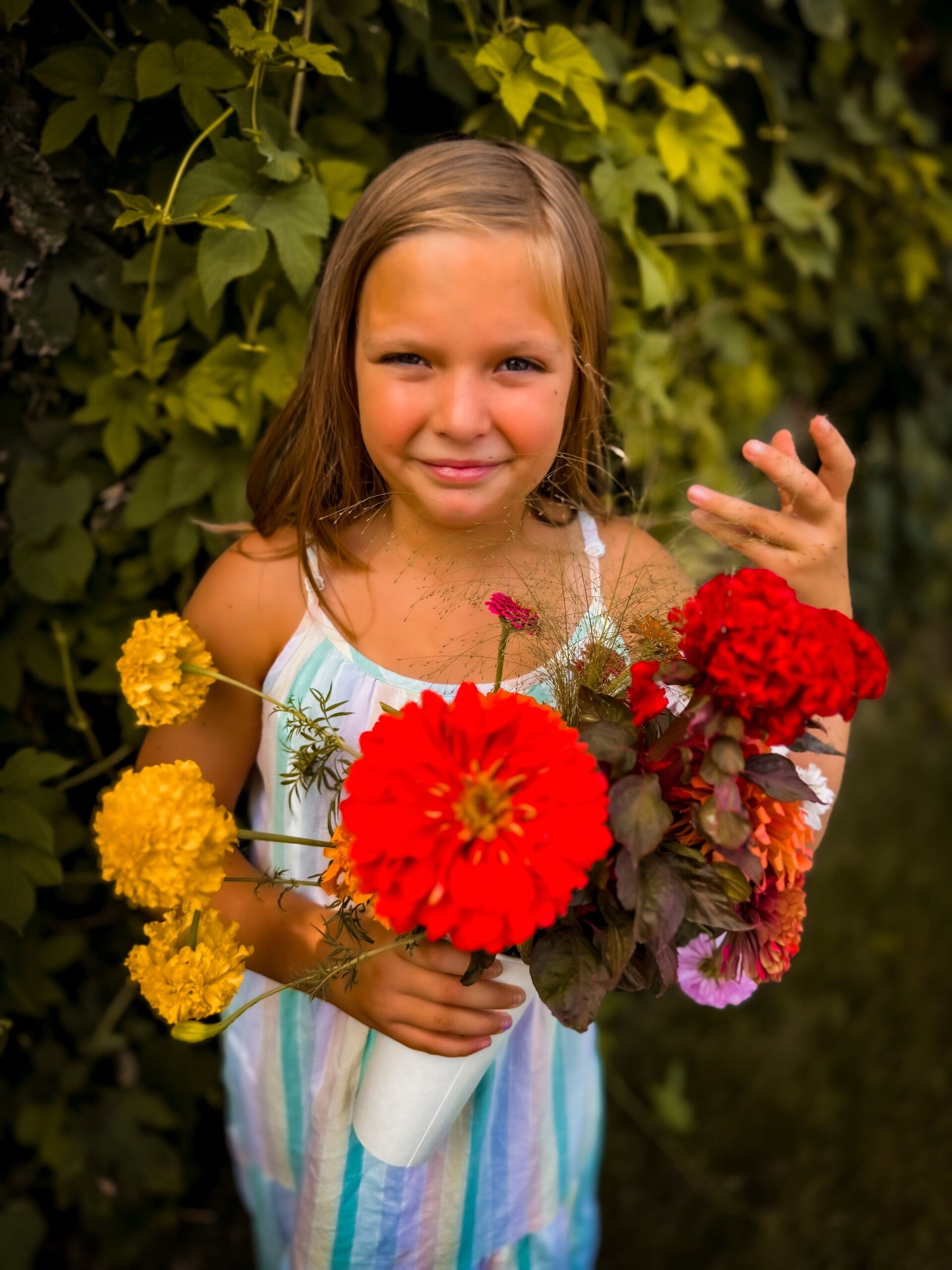 Girl holding a garden bouquet of zinnias and marigolds