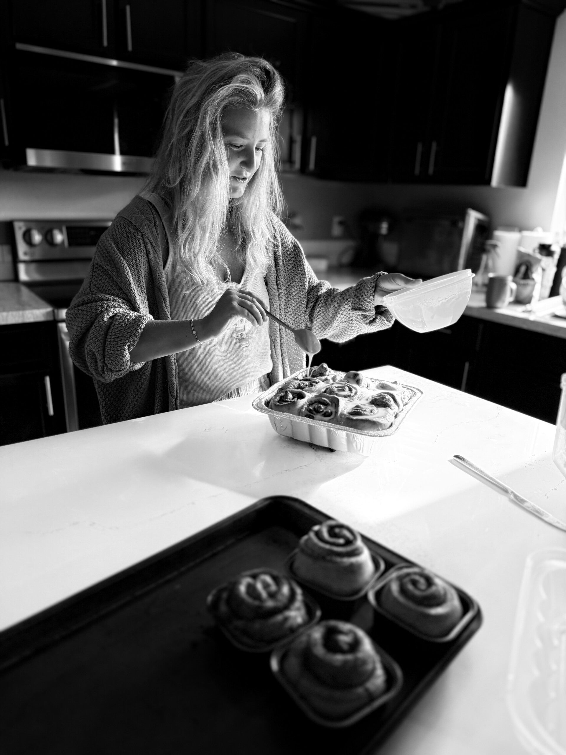 Woman laughing while cooking at a sunlit kitchen counter
