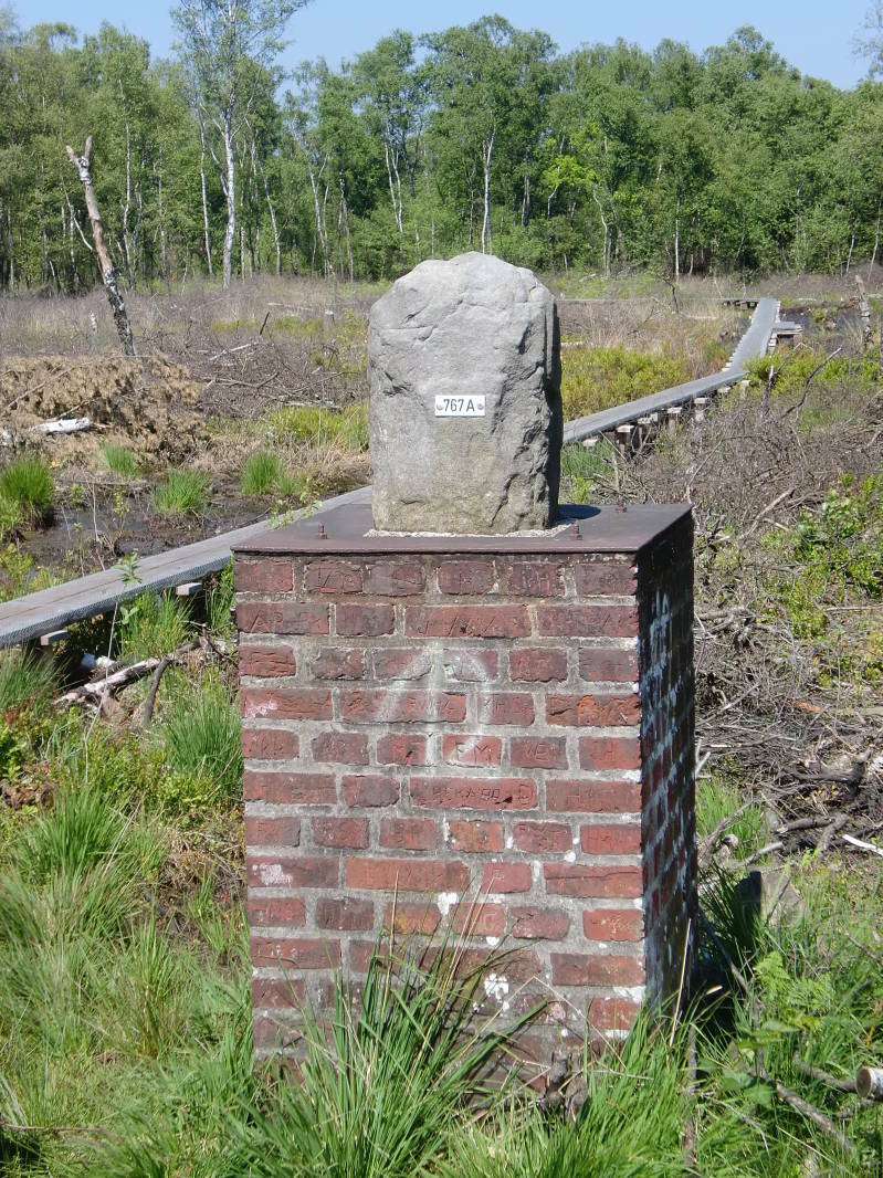Foto van grenspaal op bakstenen fundament in het Wooldsche veen