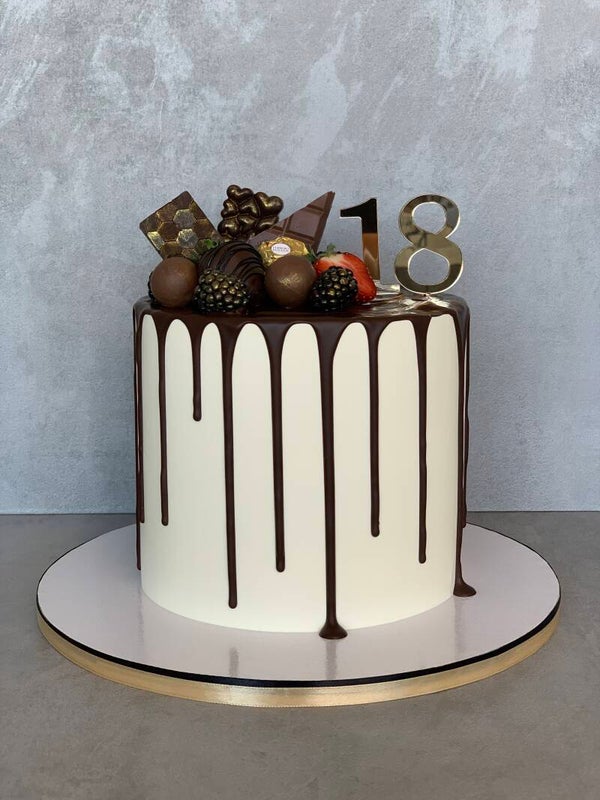 Drip Cake mit Pralinen und Beeren dekoriert