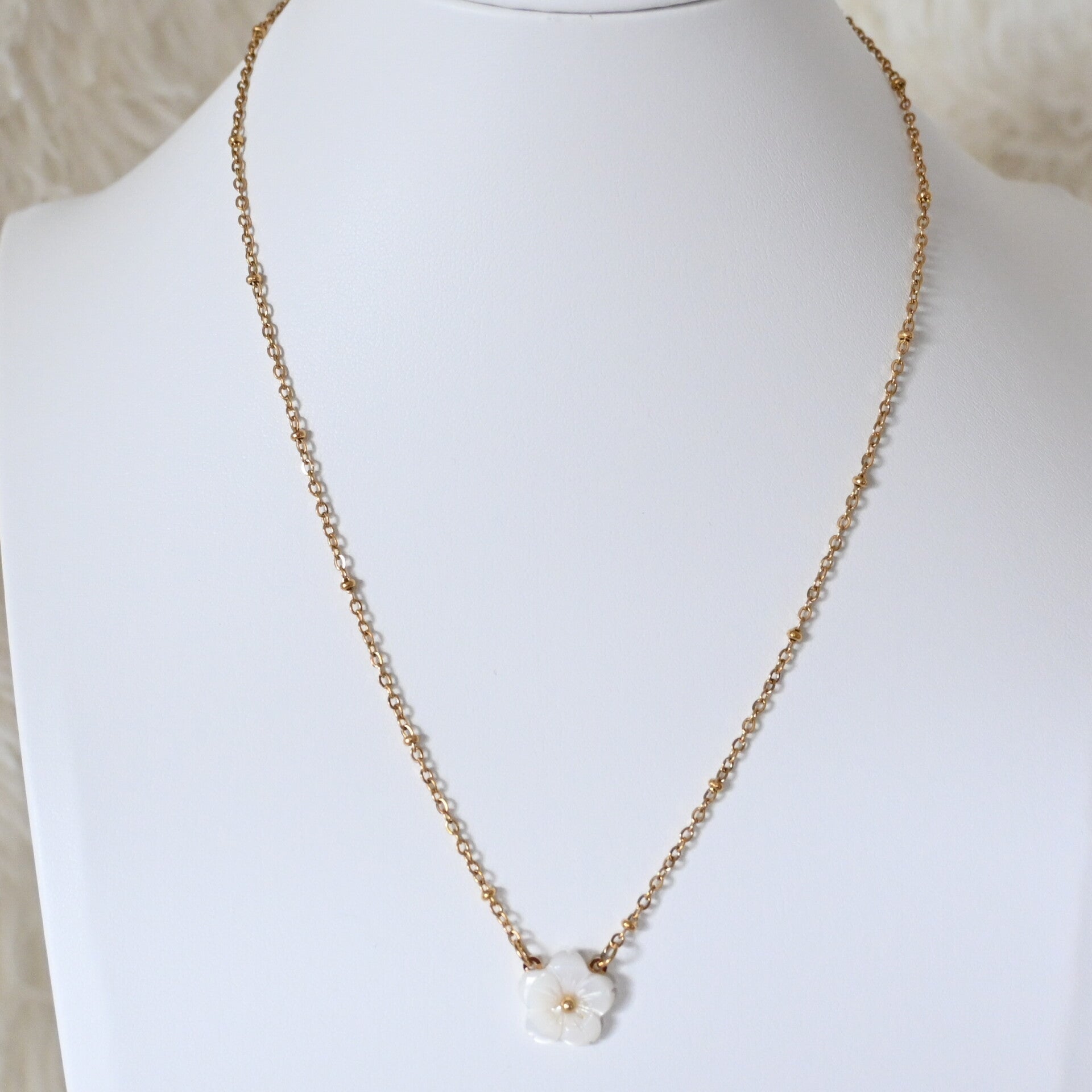 Subtiele goudkleurige ketting met wit bloemetje