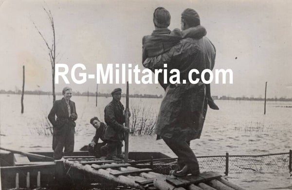 Original WW2 French Press Photo - Canadian soldier helps a civilian woman cross the water, Cleve, Germany (1945)