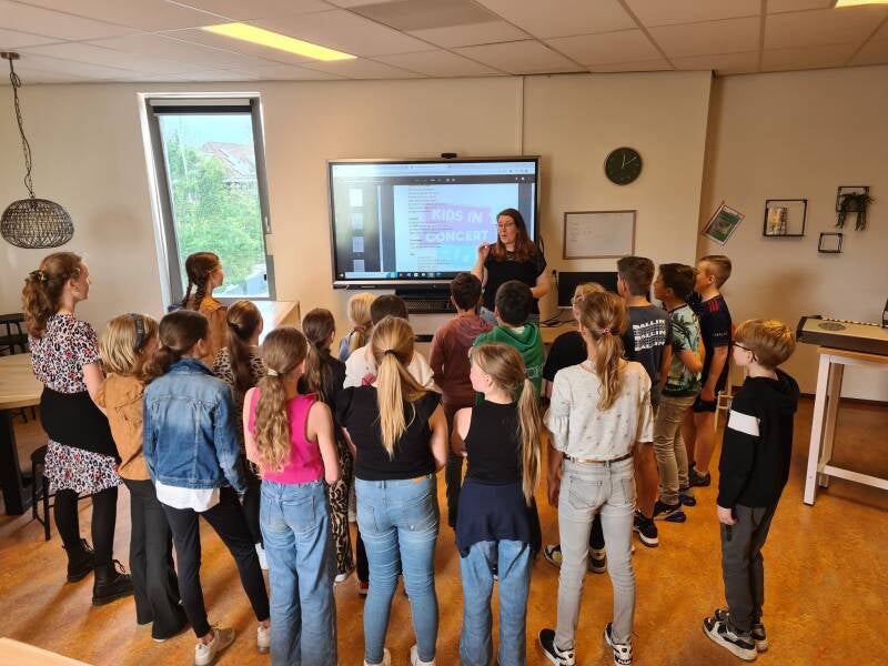 Marieke aan het werk op een basisschool met een groep kinderen. 