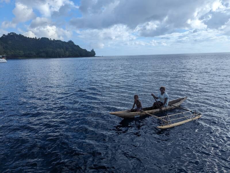 Dorfbewohner kommen in handgehauenen Einbaumkanus zum Schwimmdings um Waren zu tauschen