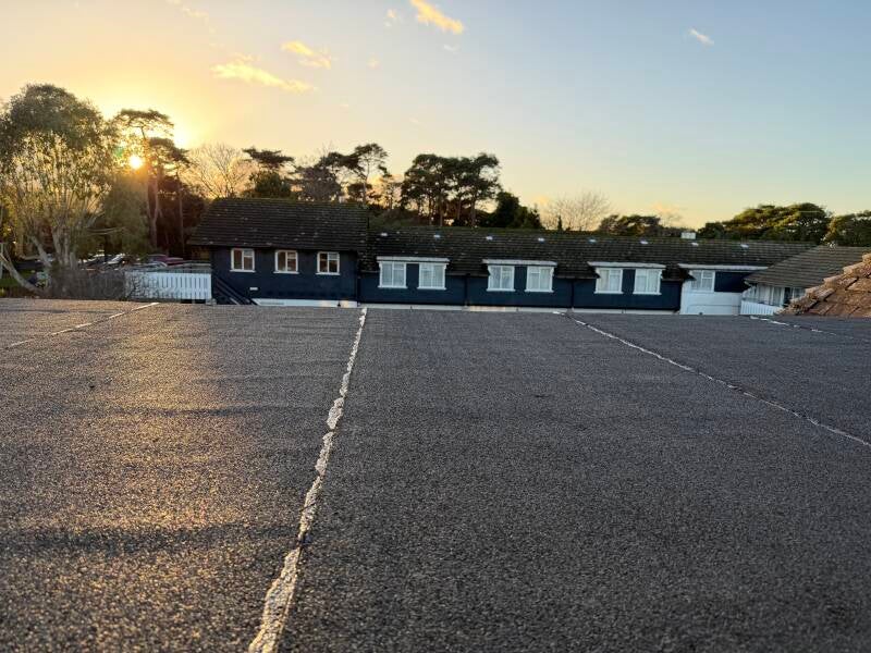 Newly installed flat roof with waterproof membrane laid across a commercial building at sunset