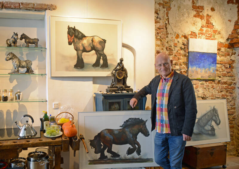 Foto: Luuk van der Werf bij een paar van de trekpaarden van Ena van Bockel Rivera in de woonkamer annex galerie en atelier © Marieke Mandemaker