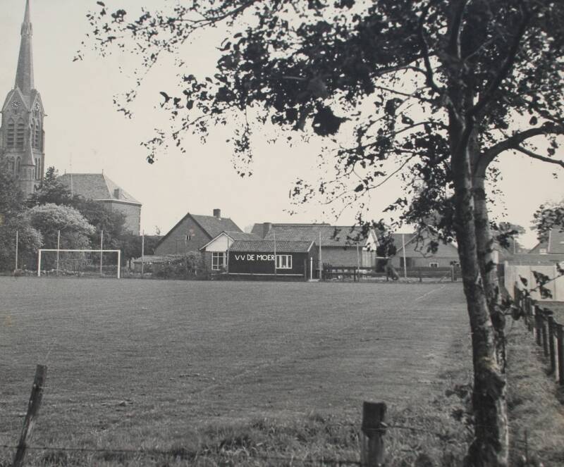 BMS0002 - Middelstraat - Zicht op het veld van voetbalvereniging "De Moer" en de St. Joachimkerk vanaf een zandpad aan de Middelstraat.