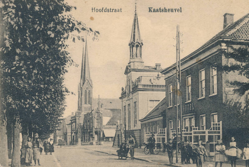 BSK0011a - Bewoners voor Hotel van den Assem, met het gemeentehuis en de St. Jan op de achtergrond, circa 1920.