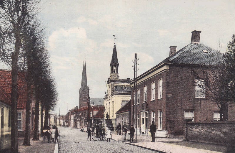 BSK0014 - Bewoners voor Hotel van den Assem, met het gemeentehuis en de St. Jan op de achtergrond, circa 1920.