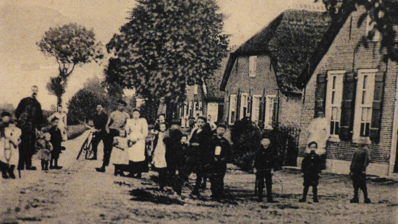 BSK0101 - De nog onverharde Kruisstraat (tegenwoordig Antoniusstraat) met een verzamelde groep bewoners die komen kijken naar de fotograaf, circa 1900.