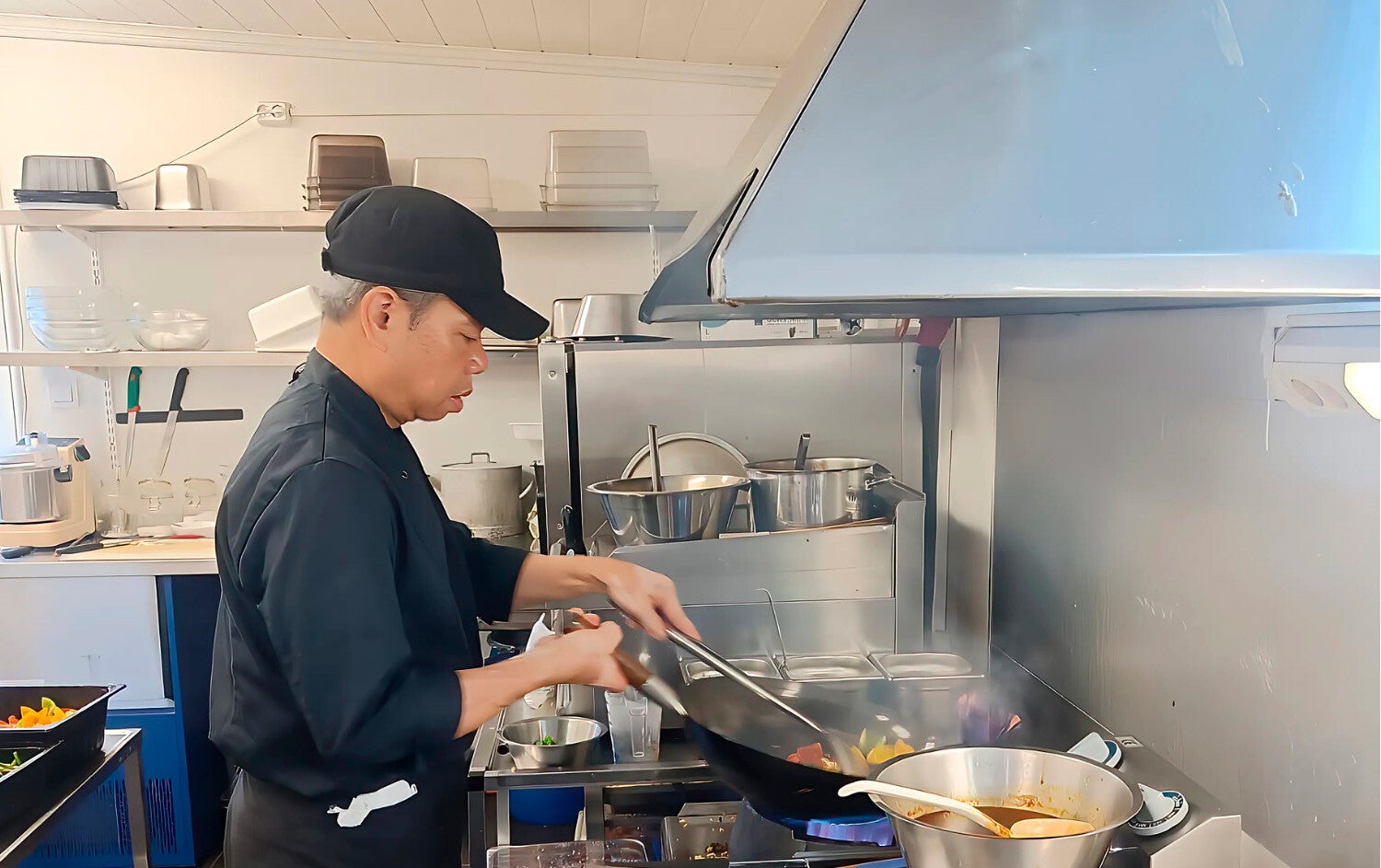 Keittiömestari Xuan, valmistamassa päivän lounasta, keittiössä, wokkipannu