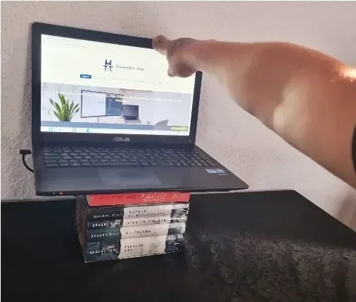 Laptop auf einem Bücherstapel als DIY-Erhöhung auf einem Schreibtisch, um eine ergonomische Augenhöhe für den Bildschirm zu erreichen.