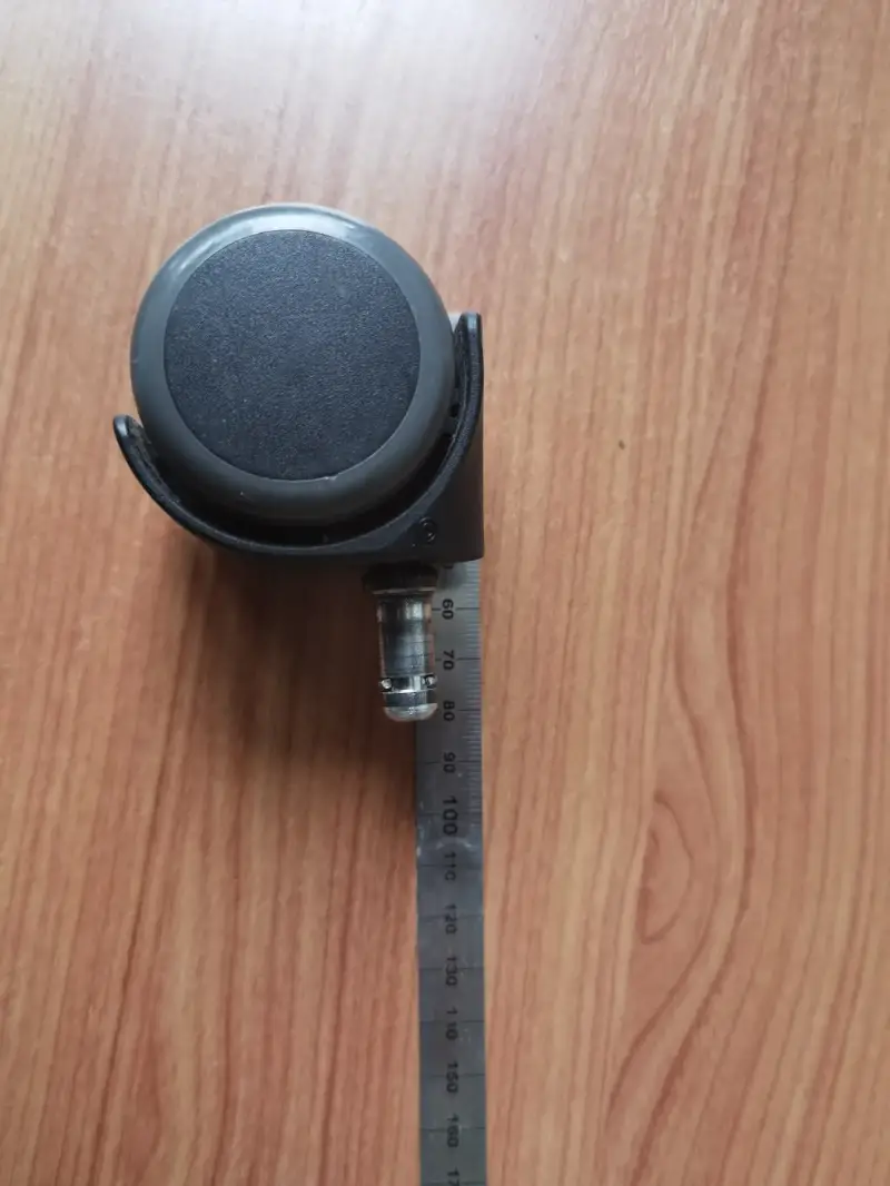Steckstift einer Bürostuhlrolle neben einem Metalllineal