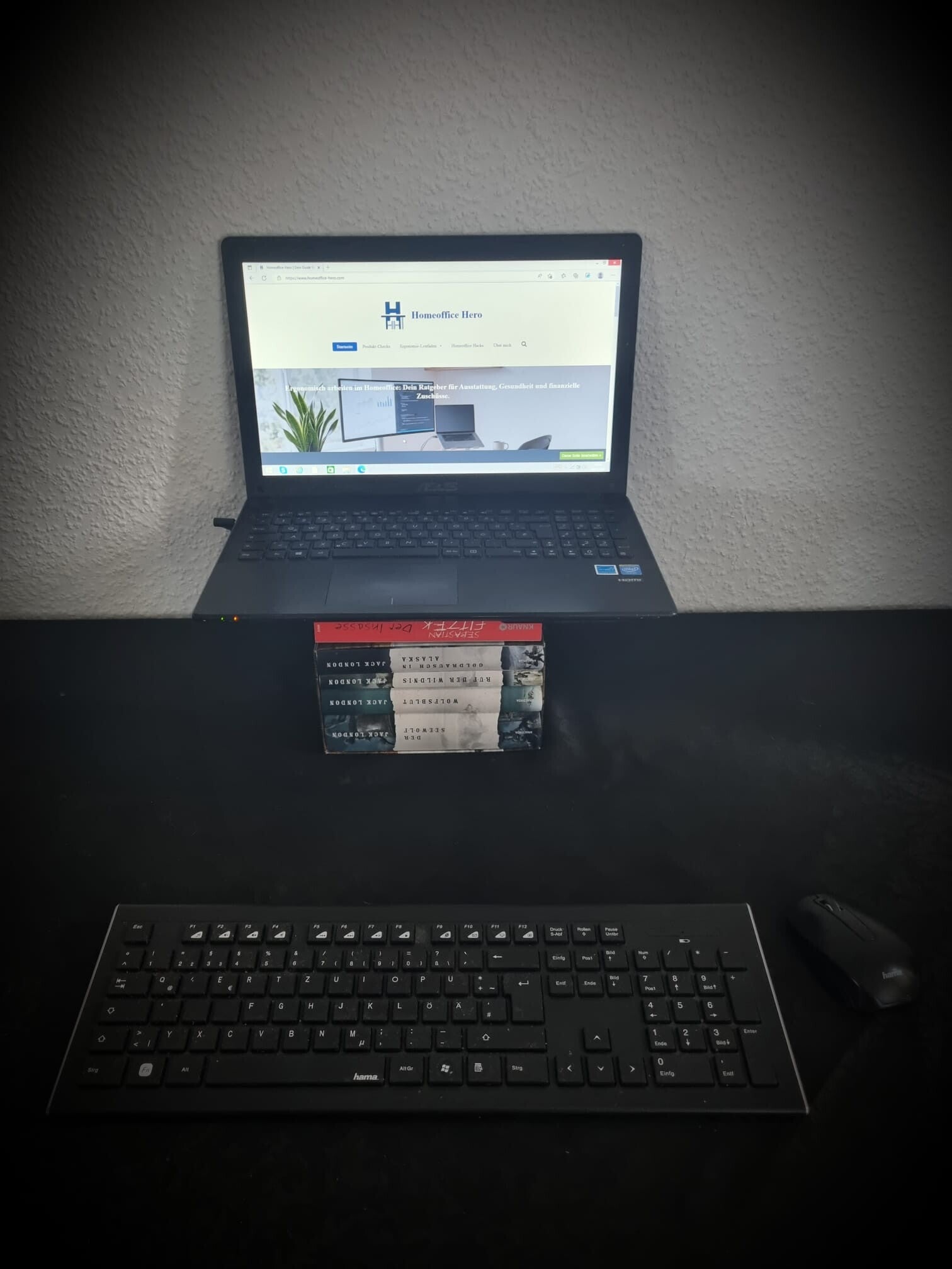 Ein Laptop auf einem Stapel Bücher. Es soll die optimale Bildschirmhöhe symbolisieren im Homeoffice.