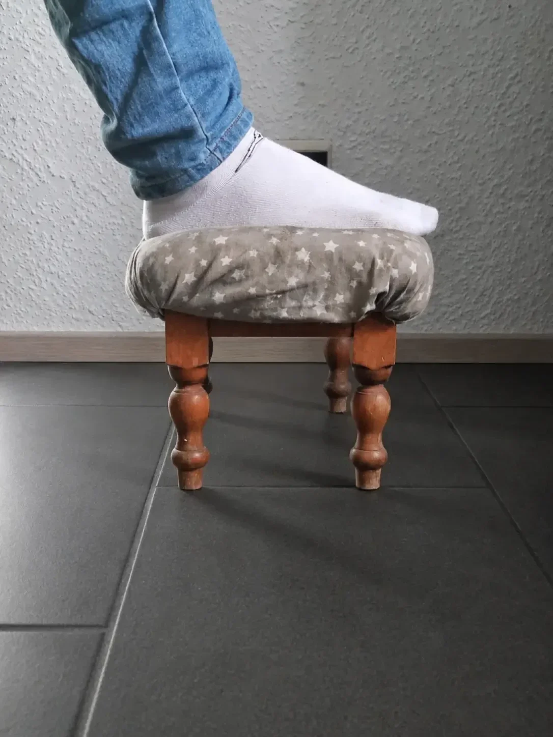 Ein alter klobiger Hocker der als Fußstütze im Homeoffice zweckentfremdet wurde und den Bedarf nach echter Ergonomie zeigt