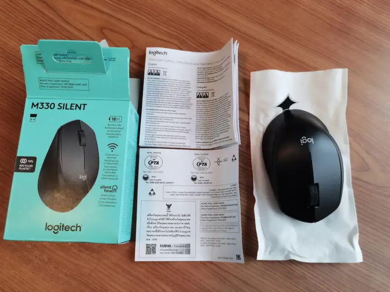 Logitech M330 neben geöffneter Verpackung und beiliegender Dokumentation