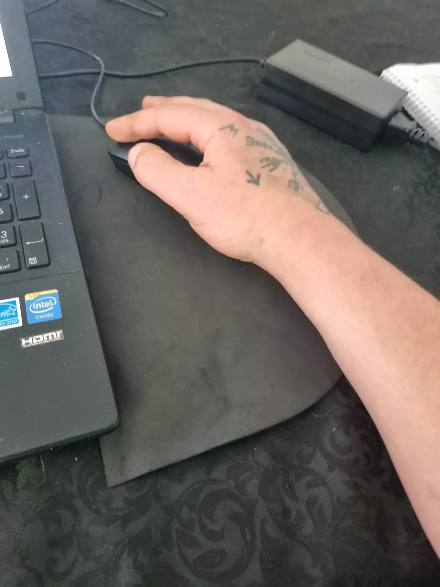 Hand liegt flach auf dem Schreibtisch und bedient eine Computermaus – typische ungesunde Haltung, die zu einem Mausarm im Homeoffice führt.