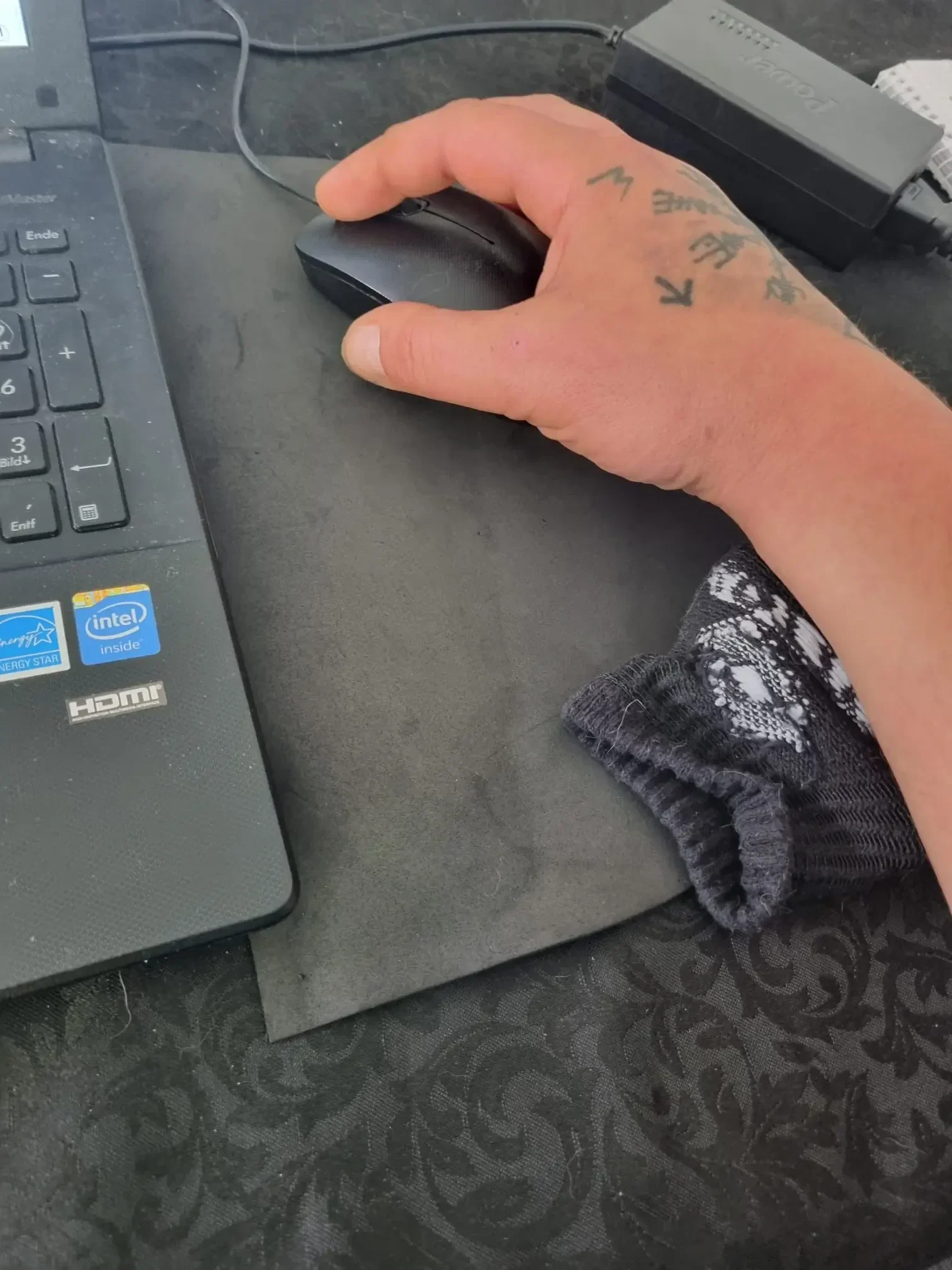 Hand bedient eine Computermaus und das Handgelenk liegt schonend auf einem gerollten Sockenbündel als kostenloser 0-Euro-Hack gegen den Mausarm.