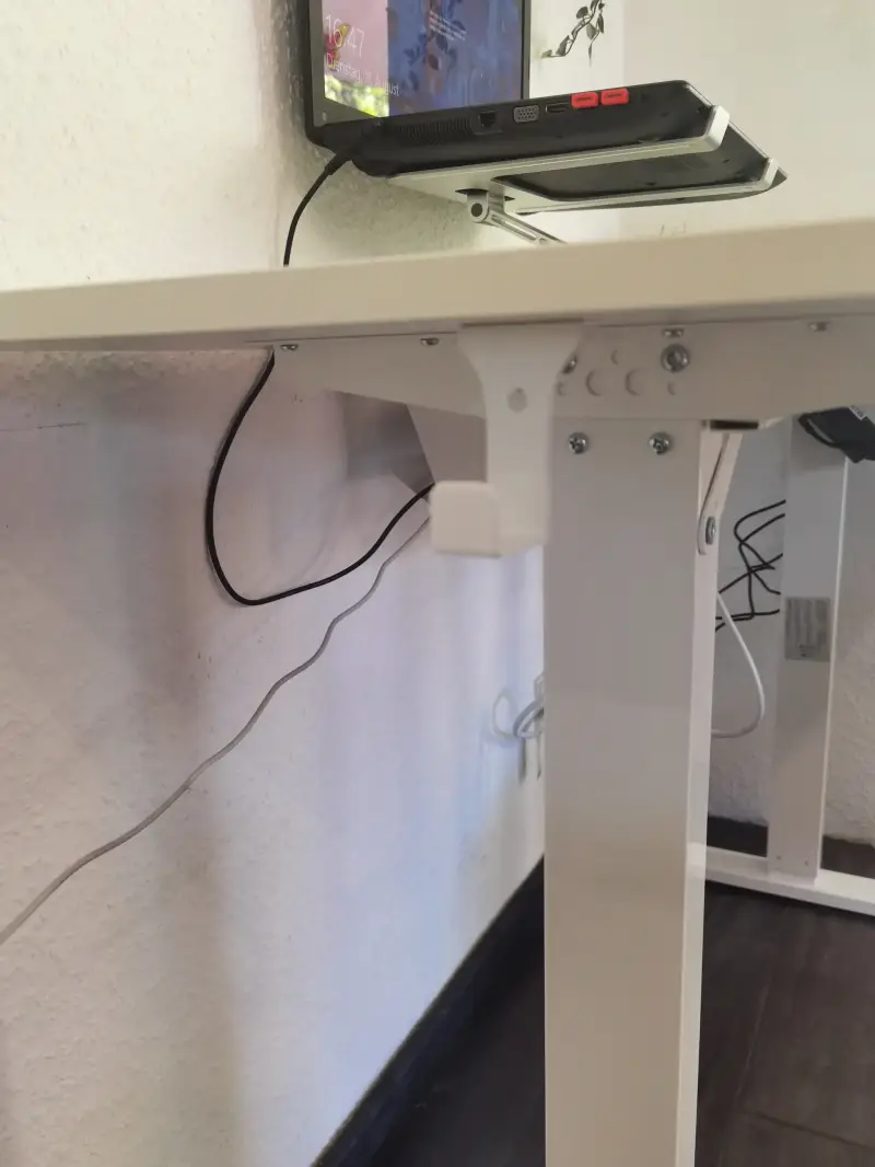 Kabelverlauf und befestigte Kabelhalterung am weißen Tischbein des SANODESK FQ2