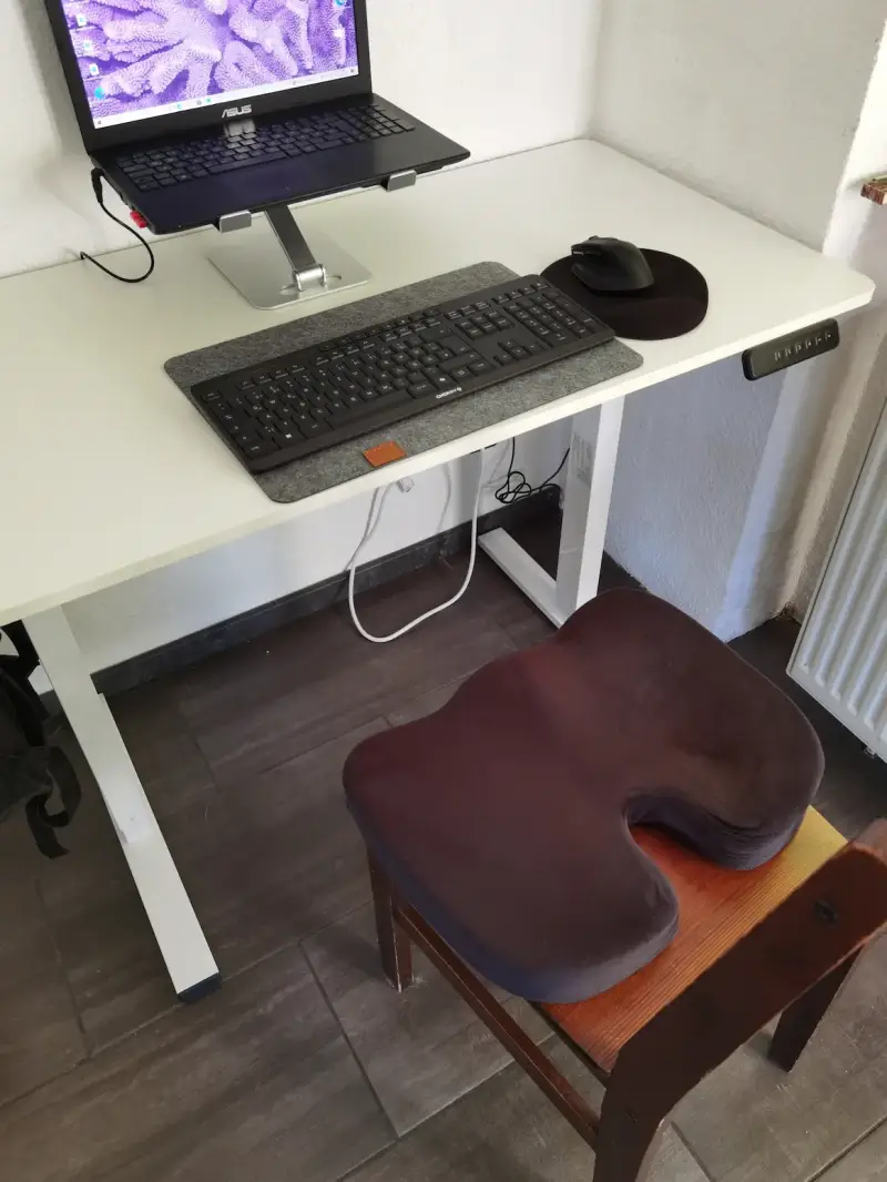 Lescars Memory-Foam-Sitzkissen auf einem Holzstuhl am Homeoffice-Arbeitsplatz während des Praxistests.