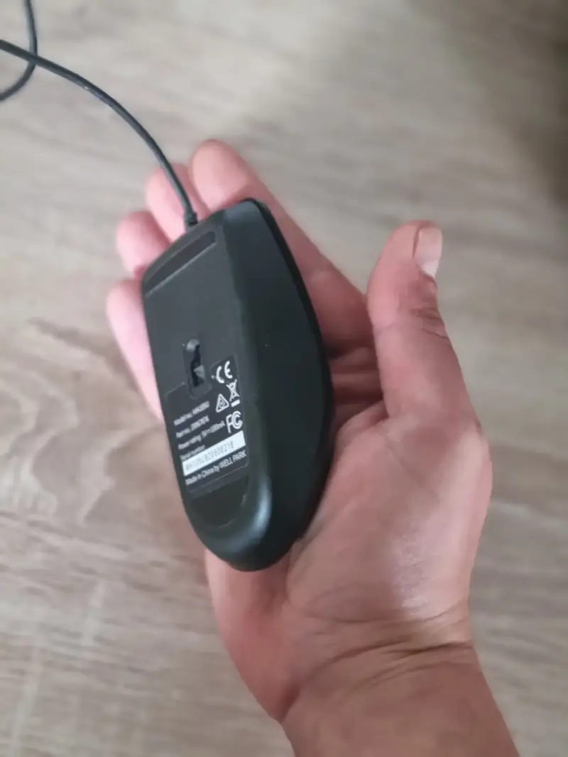 Eine zu große Hand hält eine kleine Standardmaus, was unweigerlich zu einem ungesunden Krallengriff führt.