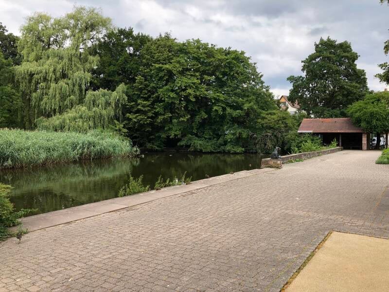 Walking along the pond, looking back to the meeting hall