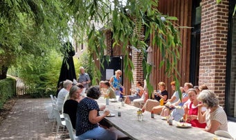 dames aan lange tafel op terras bij groepsaccomoatie zangvakantie