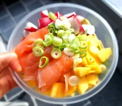 Zomerse poké bowl met zalm, mango, edamame, radijs en avocado, geserveerd in een witte kom met tahin-citroen dressing – gezond, kleurrijk en makkelijk te maken recept.