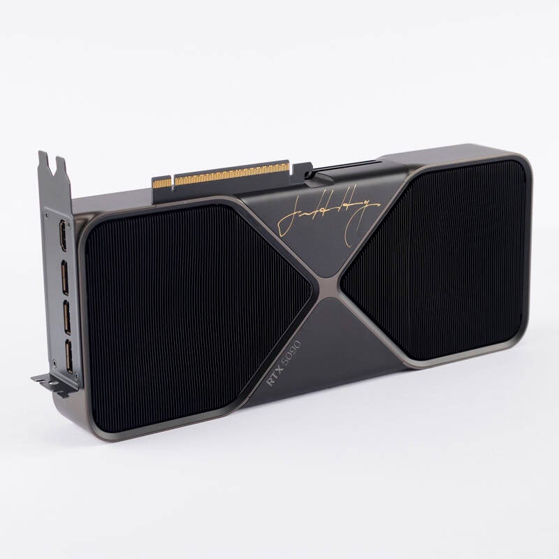 NVIDIA GeForce RTX 5090 graphics card in its original packaging, signed on the package top in black felt tip, "Jensen Huang," and on the metal housing of the card itself in gold ink, "Jensen Huang."