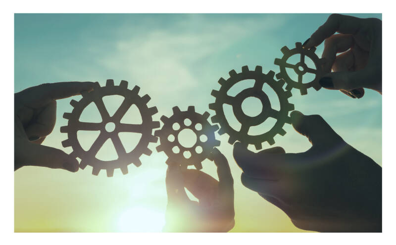 Foto van de pagina werkwijze van Agnes ten Cate Consultancy waarop vier handen zijn te zien die elk een tandwiel vasthouden waardoor er verbindingen onstaan