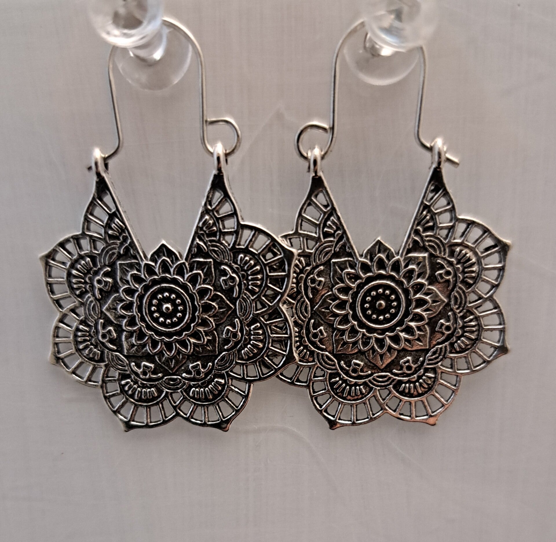 Zilverkleurige boho oorbellen in de vorm van een mandala.