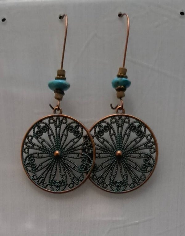 Antiek brons kleurige met groene patina boho oorbellen in de vorm van een open gewerkte mandala en synthetisch turquoise steentjes.