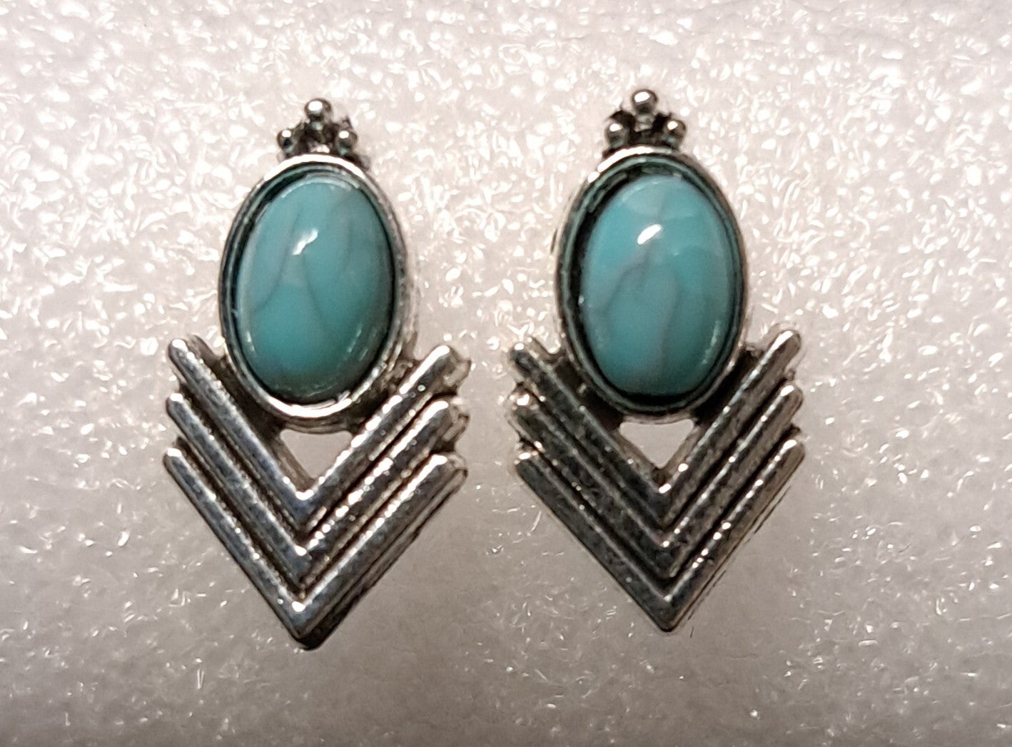 Zilverkleurige oorknopjes met synthetisch turquoise steentjes.