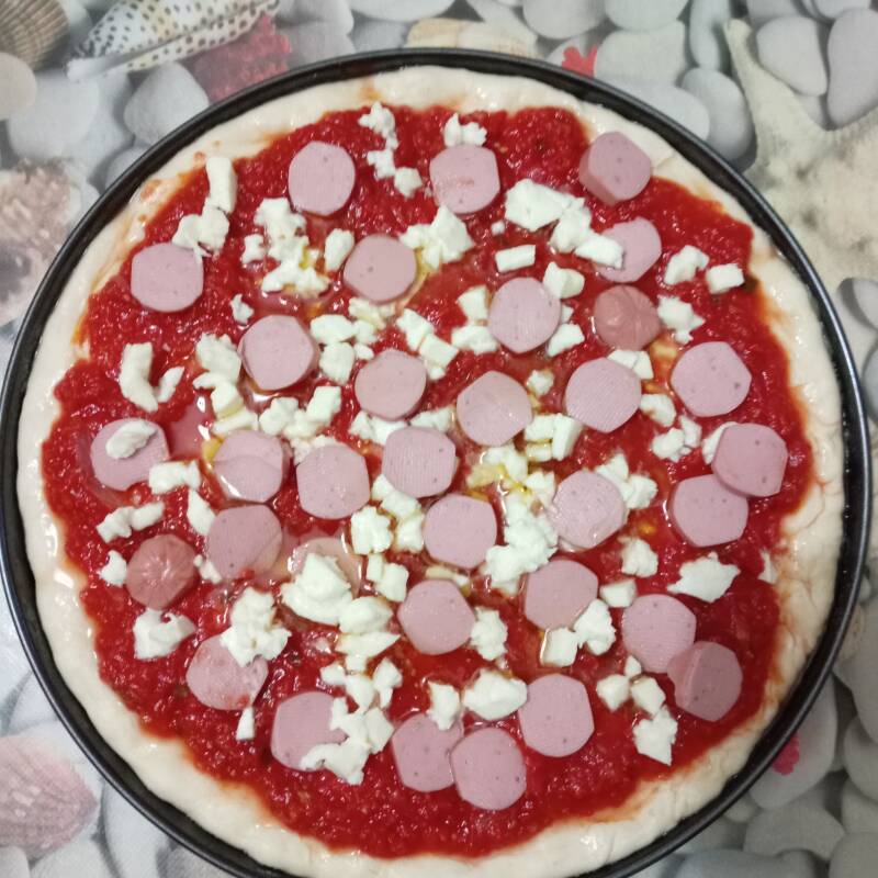 Pizza condita con: sugo, mozzarella e würstel.