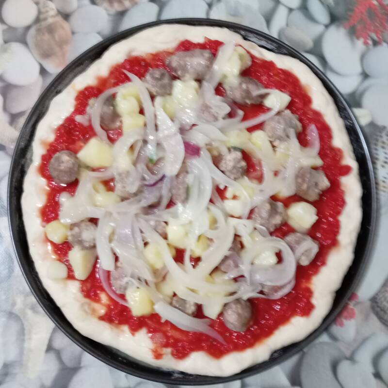 Pizza condita con: sugo,salciccia, patate e cipolla.