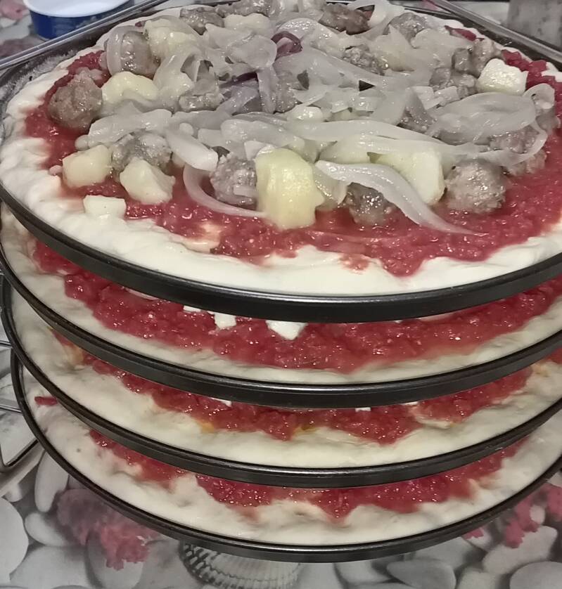 Pizze disposte su un porta pizza pronte per finire le cotura.