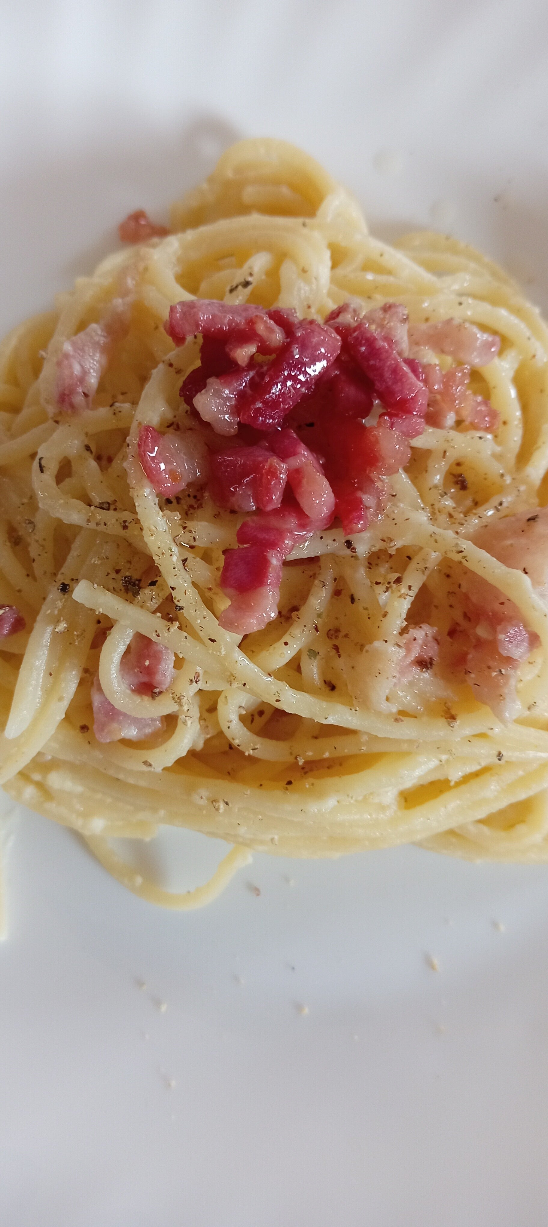 Spaghetti alla carbonara, con guanciale croccante, pecorino e pepe nero. Una ricetta tradizionale italiana perfetta per gli amanti della cucina romana.