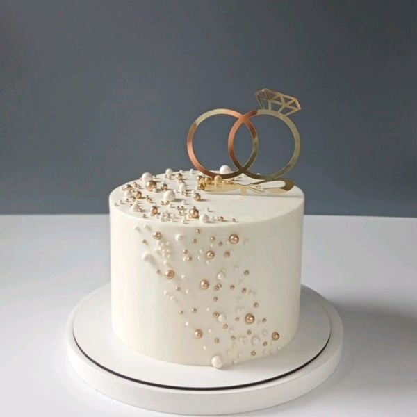 Tort weselny z perełkami i topperem – obrączki