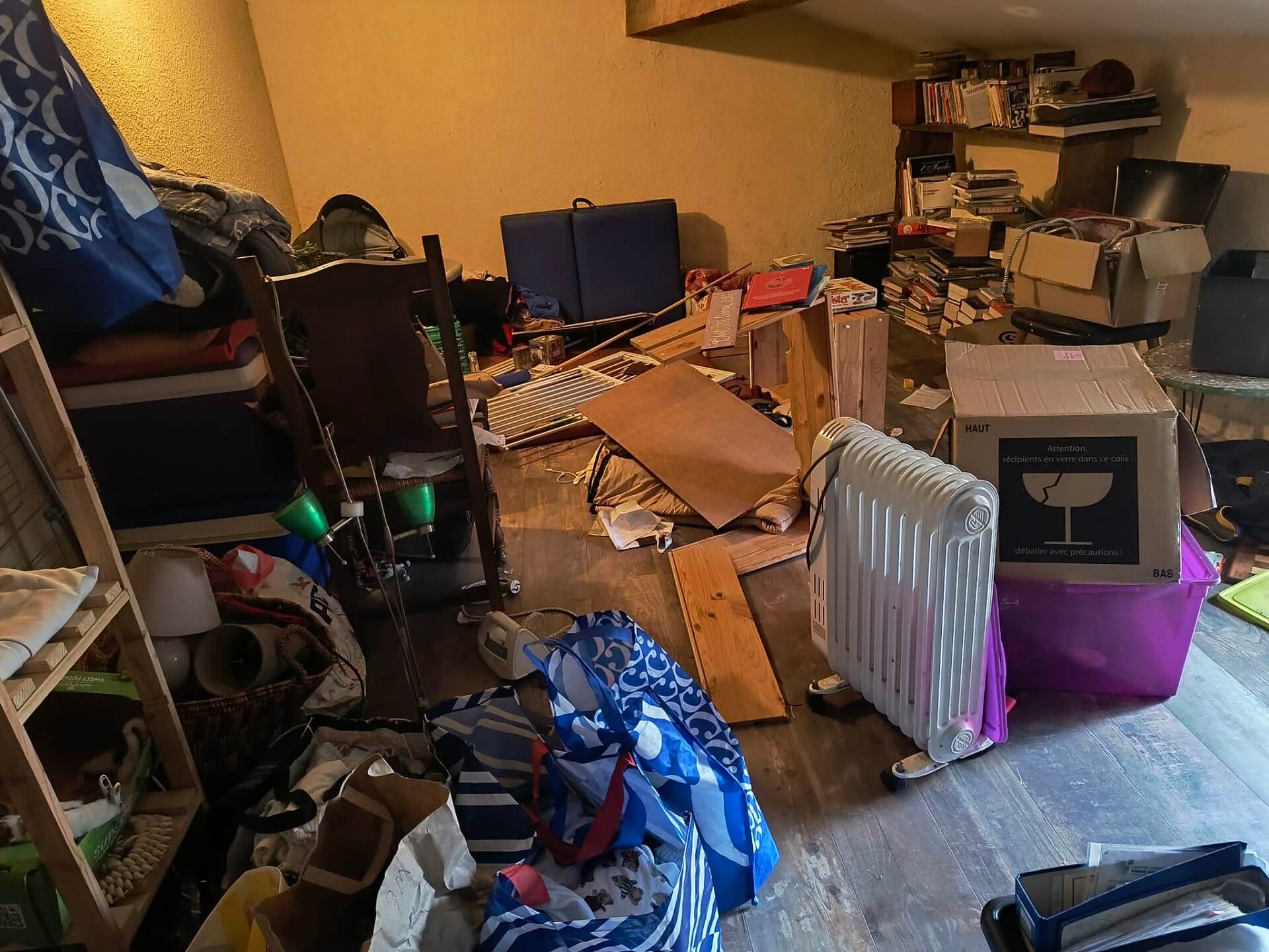 Livres, cartons et mobilier dans une pièce encombrée avant intervention — NEA