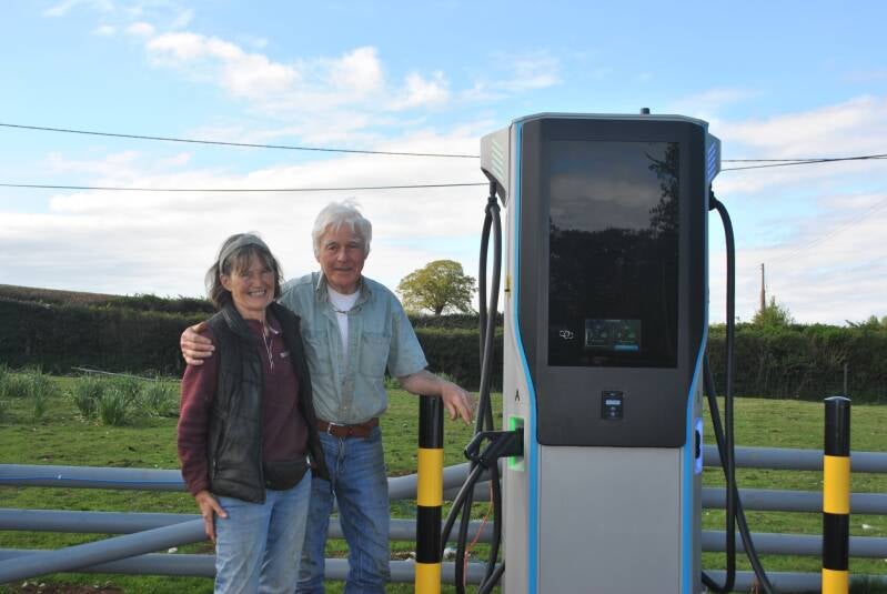 Image shows a couple stood next to a rapid charger