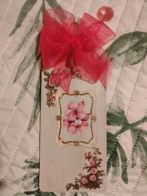 This is a home two side placque adorned with a beautiful hand tied red ribbon.  In the center is a frame with a beautiful flower inside 