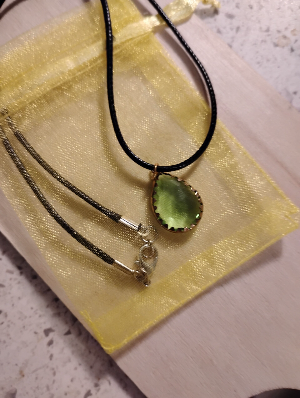 This is a necklace with a green stone attached to a leather rope.  There is a small yellow bags with it.