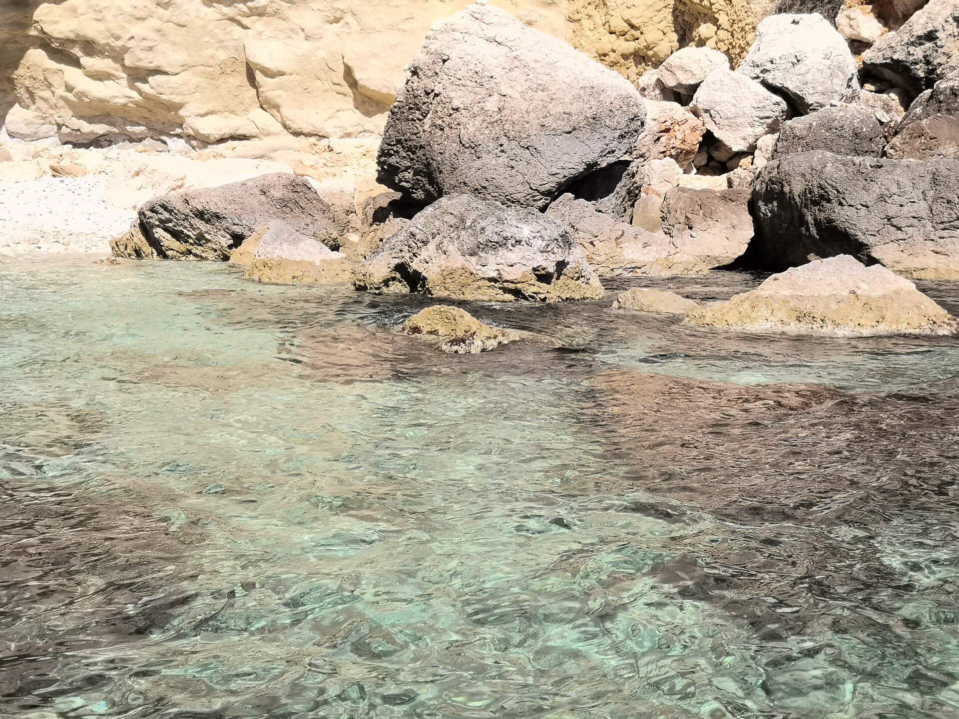 Aguas transparentes de color turquesa junto a una costa rocosa durante una excursión en barco en Cagliari, Cerdeña.