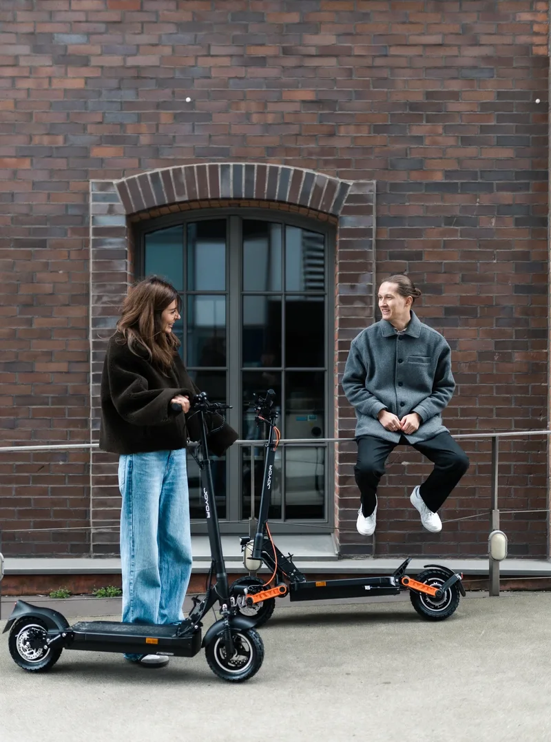 Frau auf Joyor Y8-S E-Scooter in der Stadt zusammen mit Mann