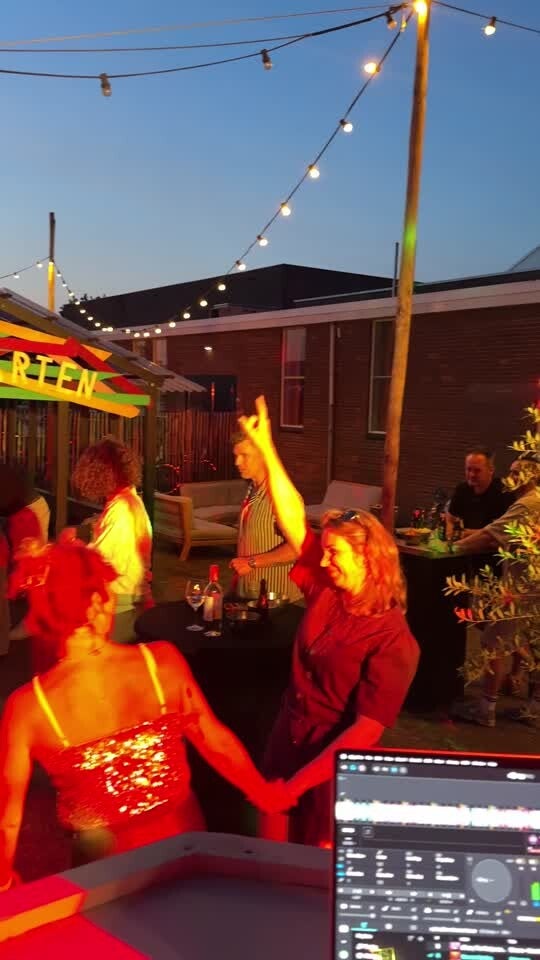 Een feest buiten onder lichtslingers bij de DJ