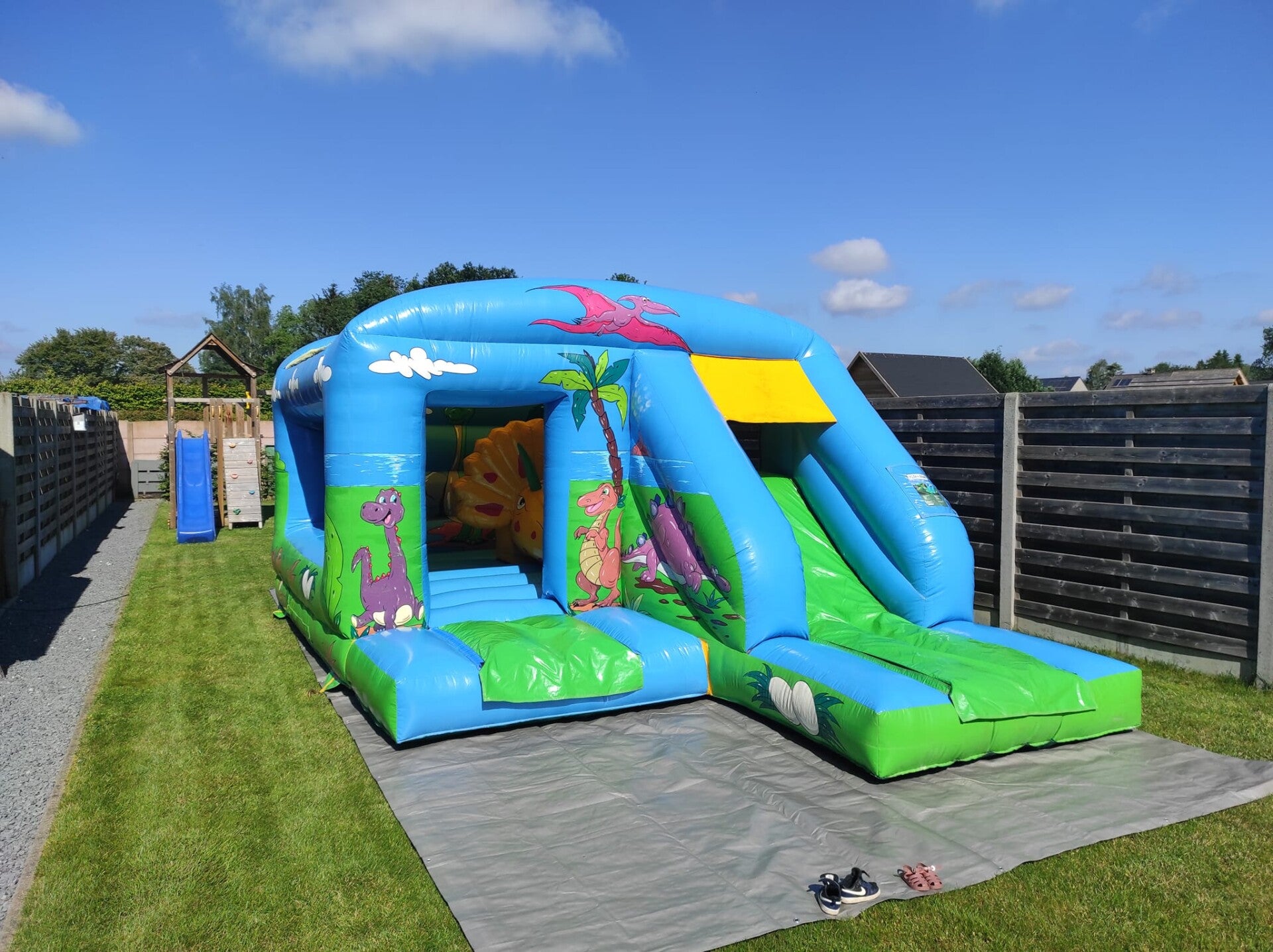Springkasteel huren met dino thema, voorzien van opblaasbaar dinosaurusfiguur en een glijbaan