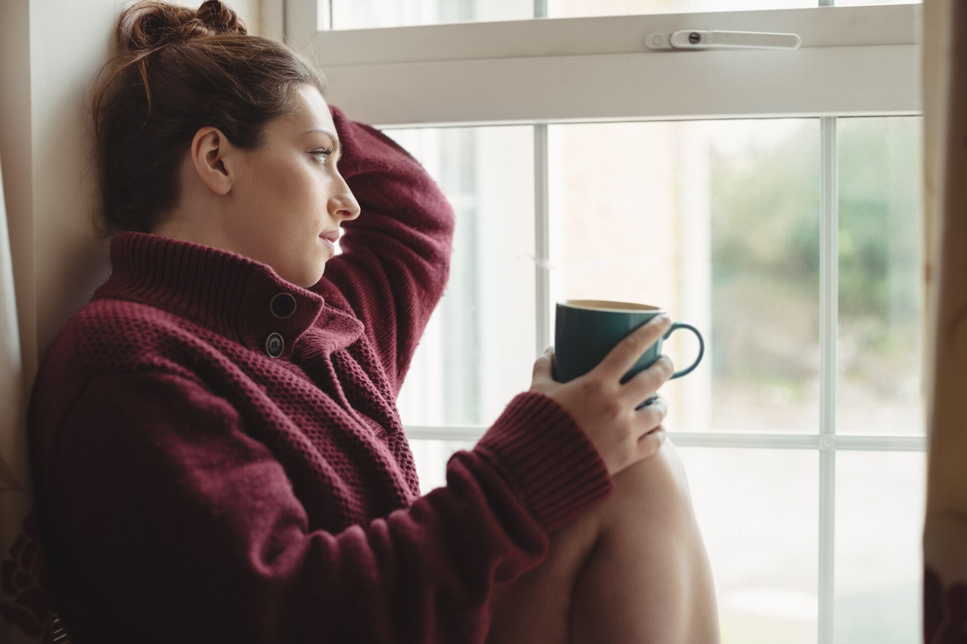 Personne fatiguée assise près d'une fenêtre après une période de stress