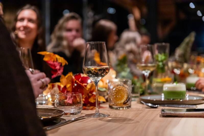 Sfeervol diner bij De Oudestraat in Neede, met gezellig gedekte tafels, wijnglazen en gasten. Culinaire arrangementen in de Achterhoek.
