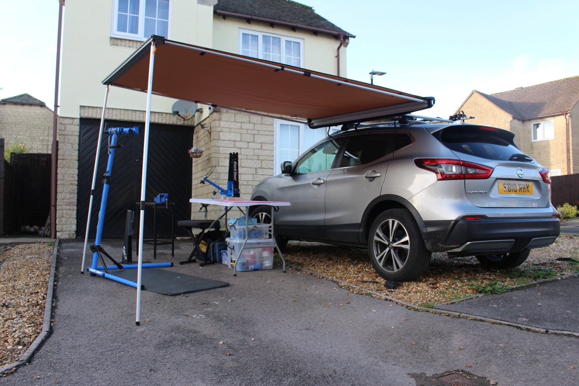 Car with a pull out canopy and arrangement of bicycle tools and equipment set up for a bicycle event evoking the image that it is set up to deal with a variety of services
